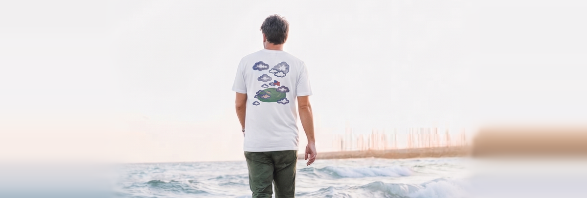 Man walking the shoreline in the Proudly Clowded golf-green cloud tee